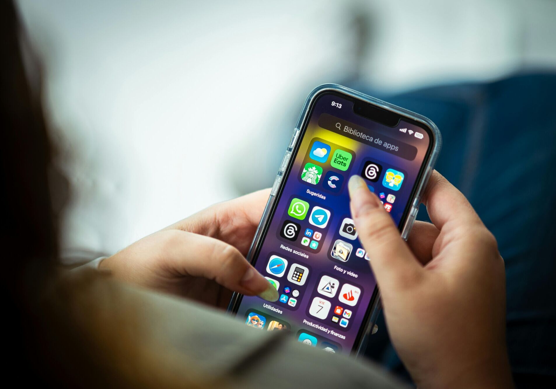 Close-up of a woman holding a smartphone displaying various apps.